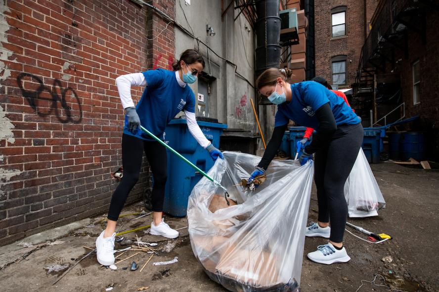 Kirsten Guerette, D24, and Jackie Flynn, D24, students at the Tufts University School of Dental Medicine, pick up litter in an alleyway on April 30, 2021. A group of student volunteers from the Tufts University Health Sciences campus took part in Love Your Block to pick up trash and plant flowers in Boston’s Chinatown.