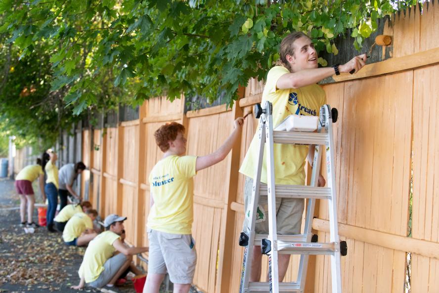 Undergraduate students paint a fence  at the Walnut Street Center in Medford as part of a Tufts community partnership for Outreach Day on September 28, 2019.