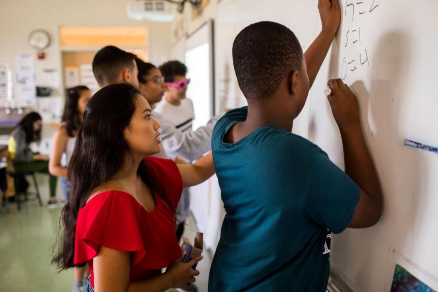 A teacher and a student work on a math problem together in a classroom at a Breakthrough Greater Boston program.