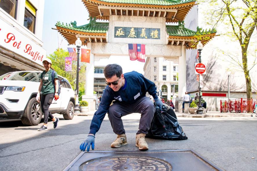 Student volunteer picking up trash at Boston's Chinatown gate