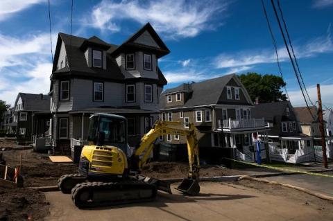 A backhoe in front of one of the Community Housing—or CoHo—project homes, new residences for juniors and seniors at Tufts, one of the many construction projects under way at the university this summer.