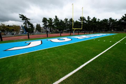 A closeup view of the football field endzone, with Jumbos written on it. The new turf field and other upgrades at Ellis Oval are a boost for Tufts football and other teams and the entire community.