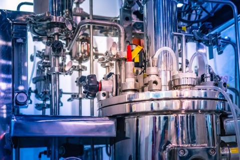 Complex laboratory equipment, with a stainless-steel base and many tubes coming out of it. Tufts researchers receive up to $4.5 million from DARPA to create robust, flexible biosynthetic manufacturing 