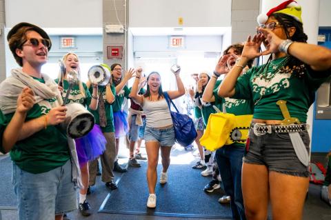 A student walks through a gauntlet of cheering students. 