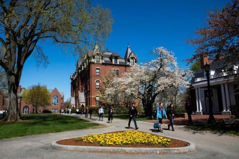 Students walk in front of Tufts’ East Hall on a spring day.