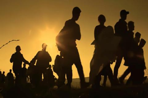 Migrants walking along a track, seen in profile only.
