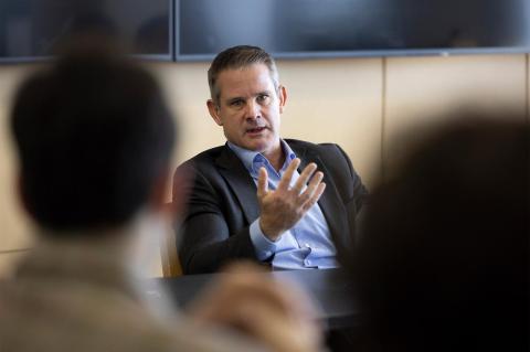 Adam Kinzinger speaks to a group of students while sitting at a table.