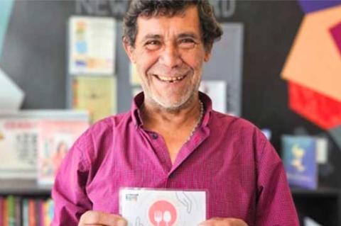 A man in a pink shirt holds a coupon-sized voucher in his hands