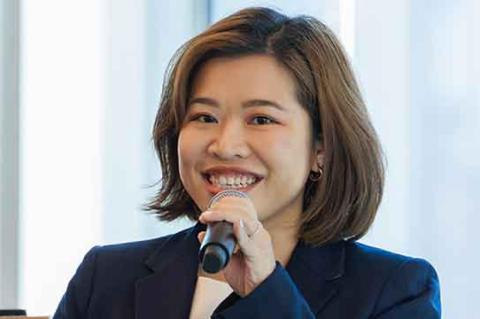 a woman in a navy blazer and white dress with a microphone