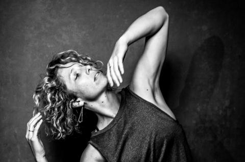 Stevie Oakes, a physical therapy student, dances in a tank top against a dark background in a black-and-white photo